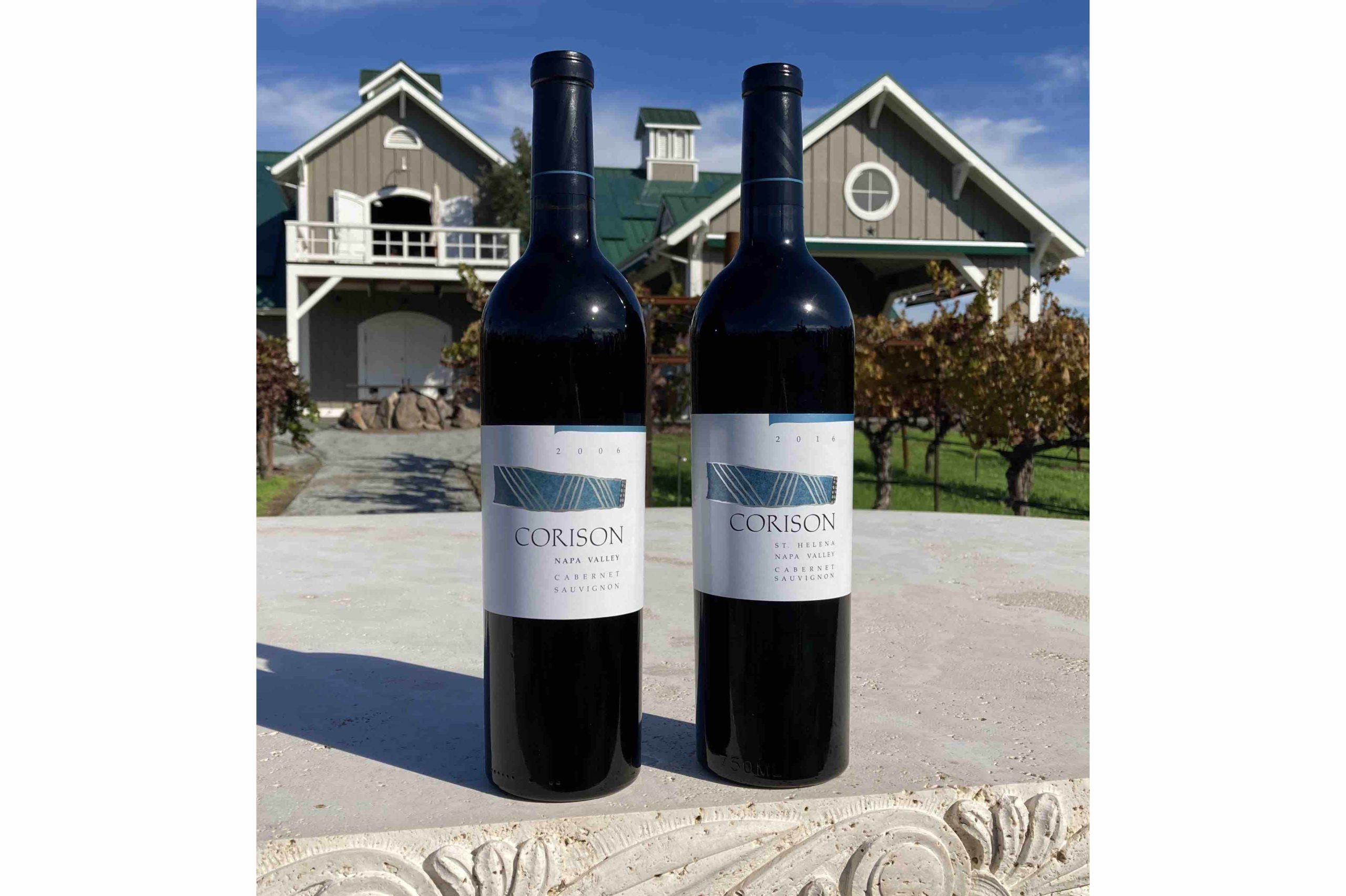 A bottle each of the 2006 and 2016 Corison Napa Valley Cabernet Sauvignon with the winery in the background