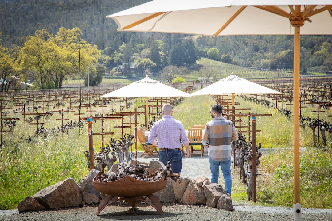 Two people walking out into Kronos Vineyard at a Corison party