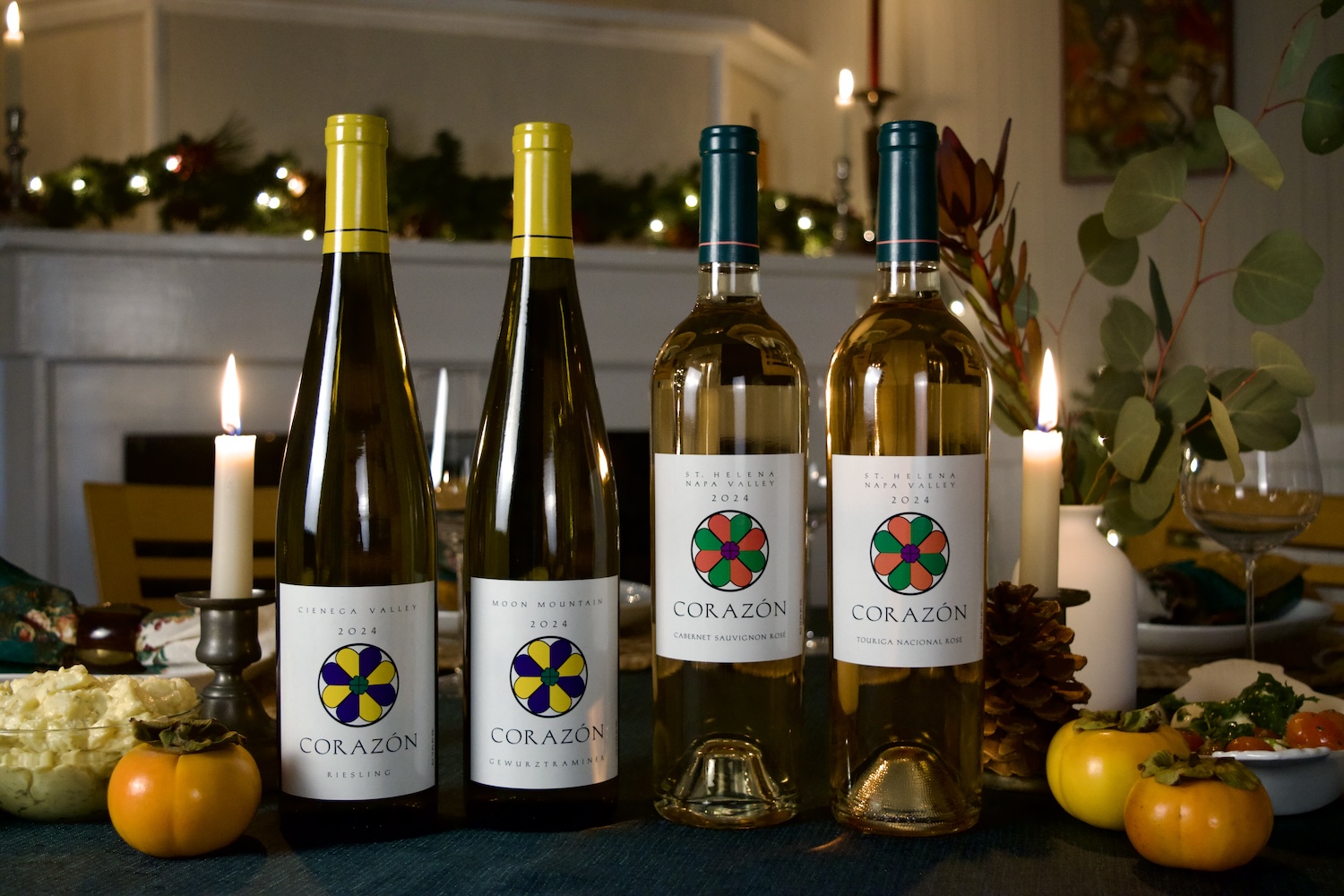 A bottle each of the 2024 Corazón Cienega Valley Riesling, the 2024 Corazón Moon Mountain Gewürztraminer, the 2024 Corazón St. Helena Napa Valley Cabernet Sauvignon Rosé, and the 2024 Corazón Touriga Nacional Rosé, on a festive holiday table.