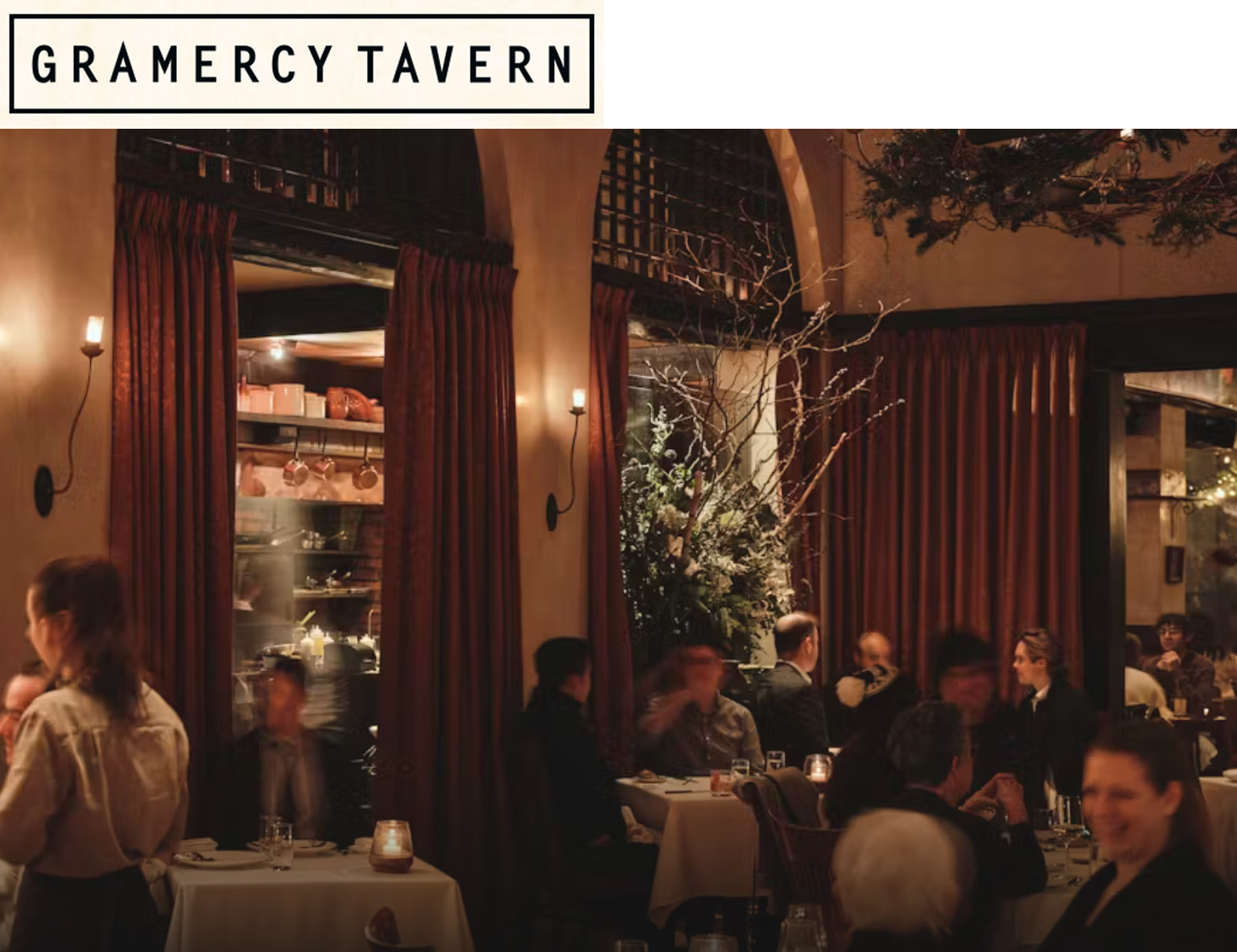 Photo of the Gramercy Tavern Dining Room with people seated at tables lit by candlelight.